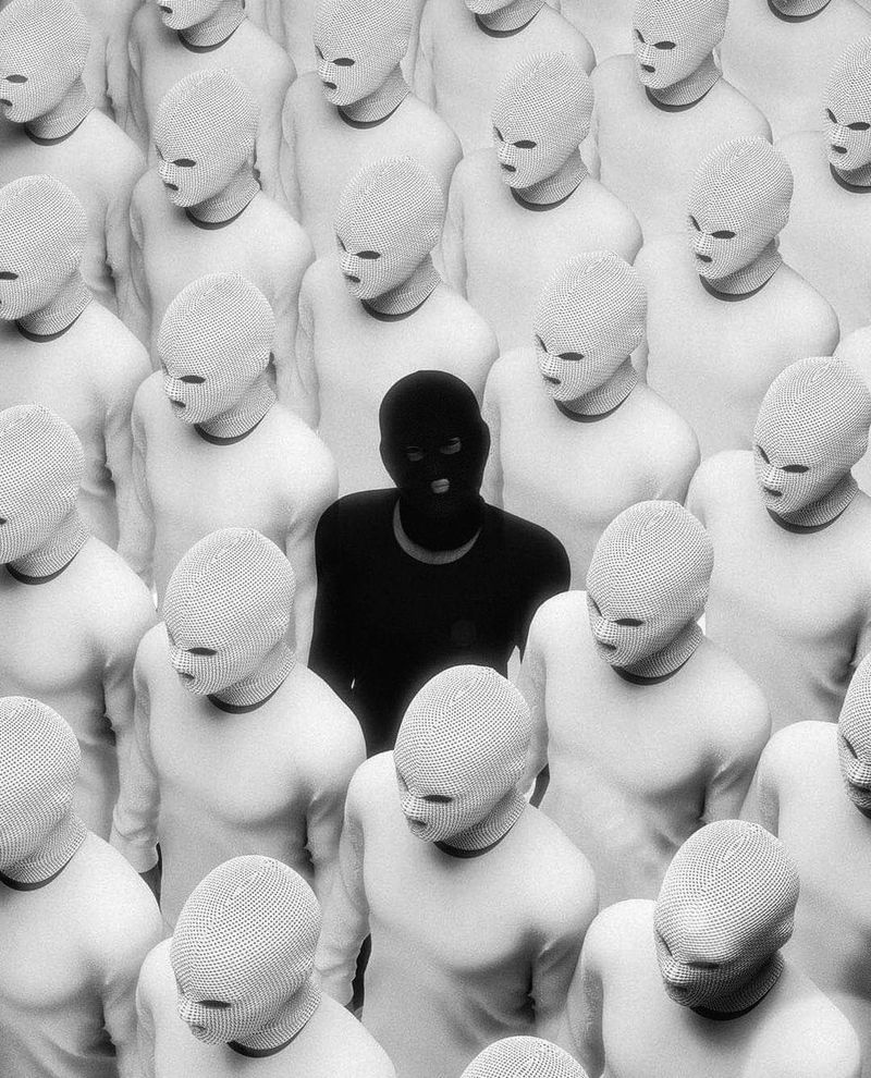 un homme en noir parmi une foule d'hommes en blanc comme un mouton noir qui détonne