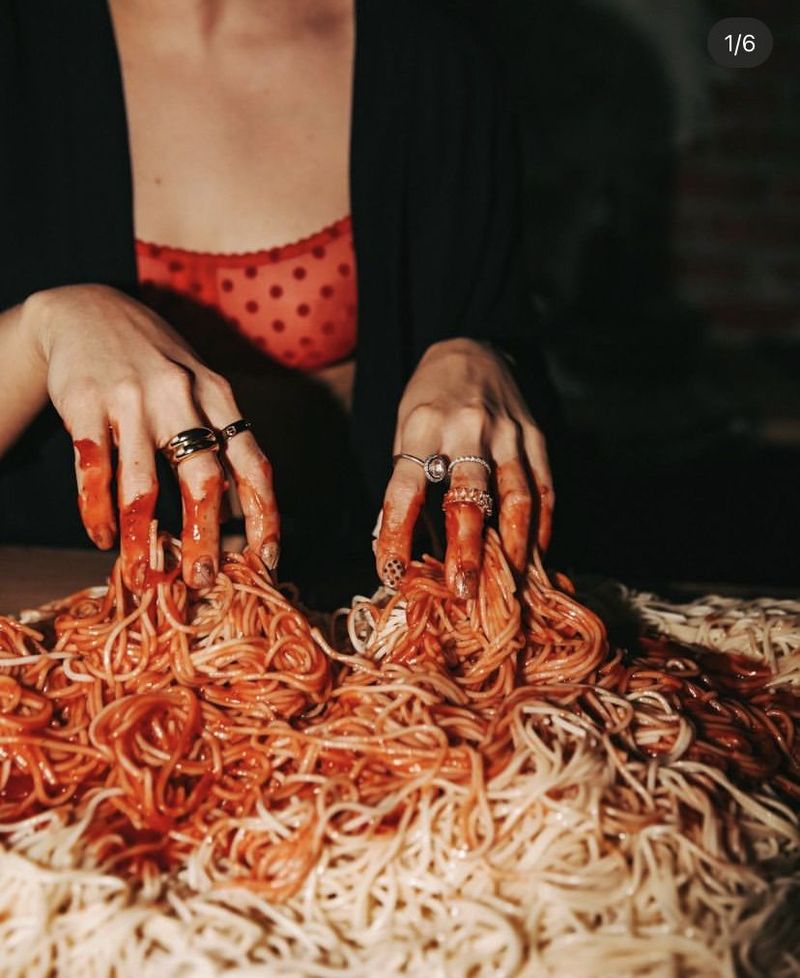 Mains baguées qui plongent dans un plat de spaghettis à la sauce tomate