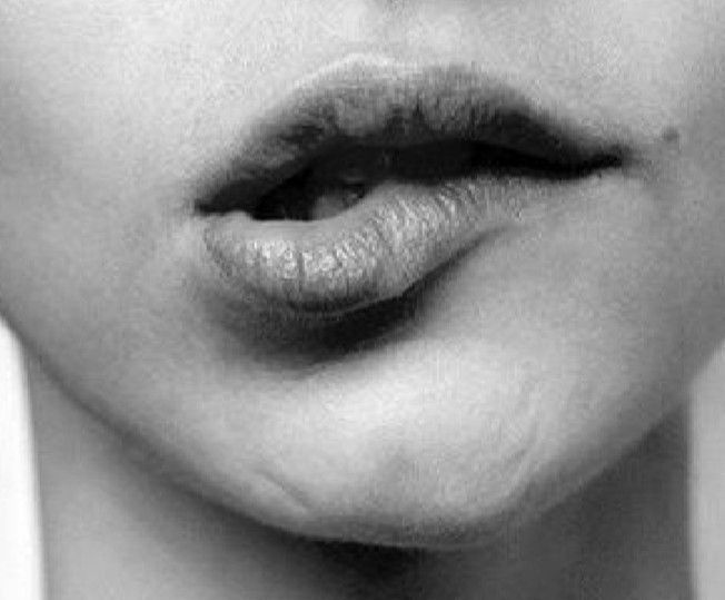 Gros plan en noir et blanc d'une bouche qui se mord la lèvre inférieure