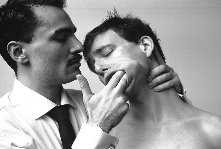 Photo en noir et blanc d’un homme en costume qui tient fermement le visage d’un autre homme