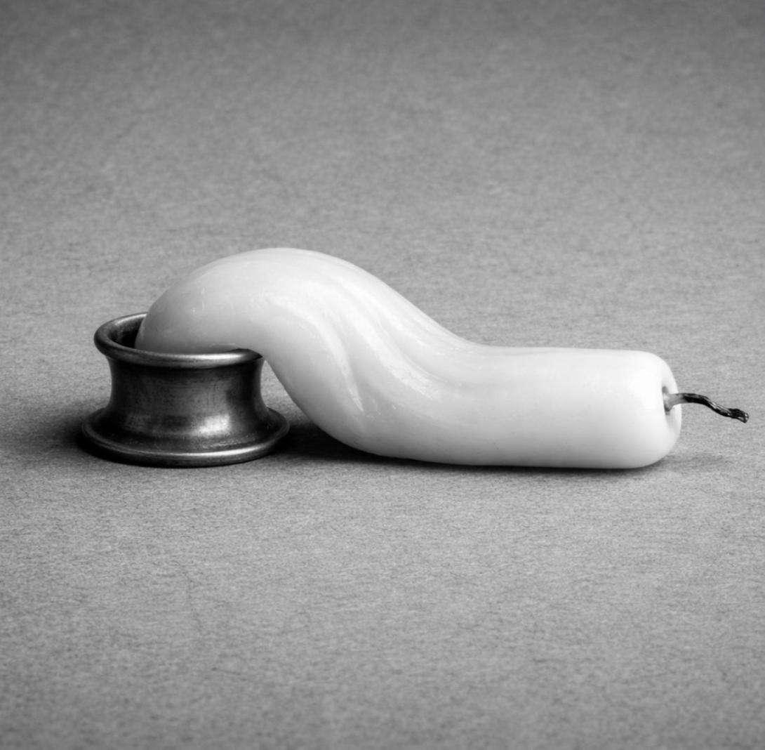 Nature morte en noir et blanc d'une bougie blanche ramollie qui s'affaisse hors de son bougeoir en métal