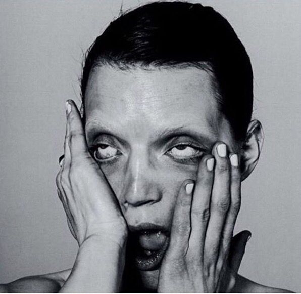 Portrait en noir et blanc d'une femme, les mains sur les joues, les yeux levés au ciel et la bouche ouverte
