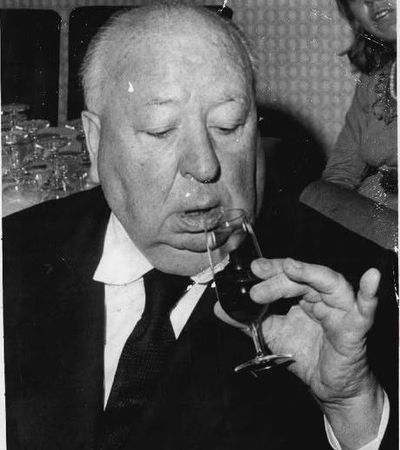 Photo en noir et blanc d'un homme âgé en costume qui boit dans un verre à pied lors d'une réception